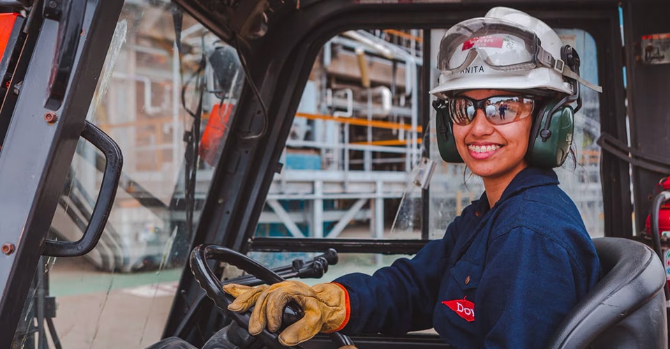A smiling female Dow employee driving a fork truck
